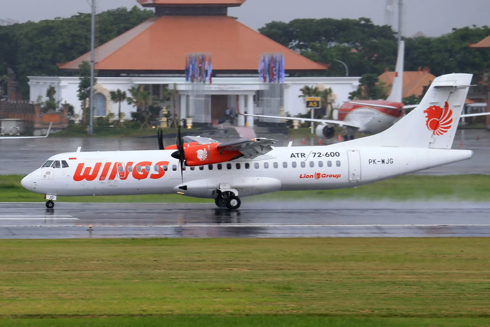 Avion à hélices ATR 72 sur le tarmac de l'aéroport de Bali, devant un bâtiment au toit balinais