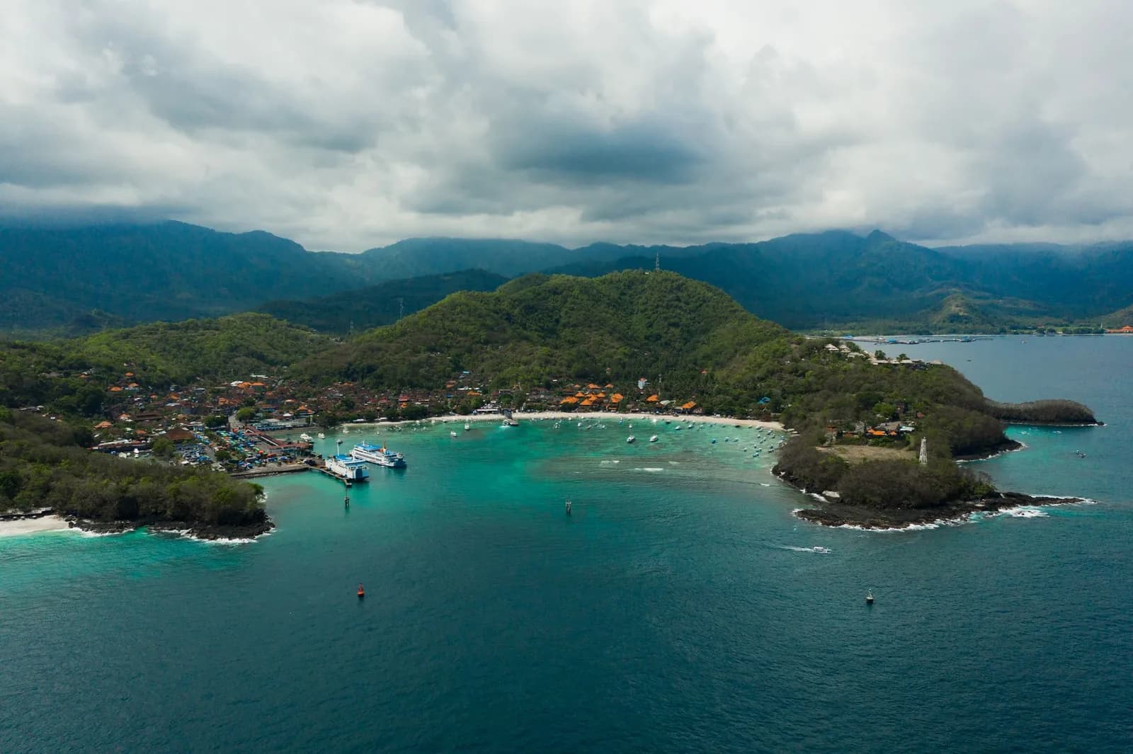 Vue aérienne du port de Padang Bai à Bali, avec ferry, bateaux et plage dans la baie