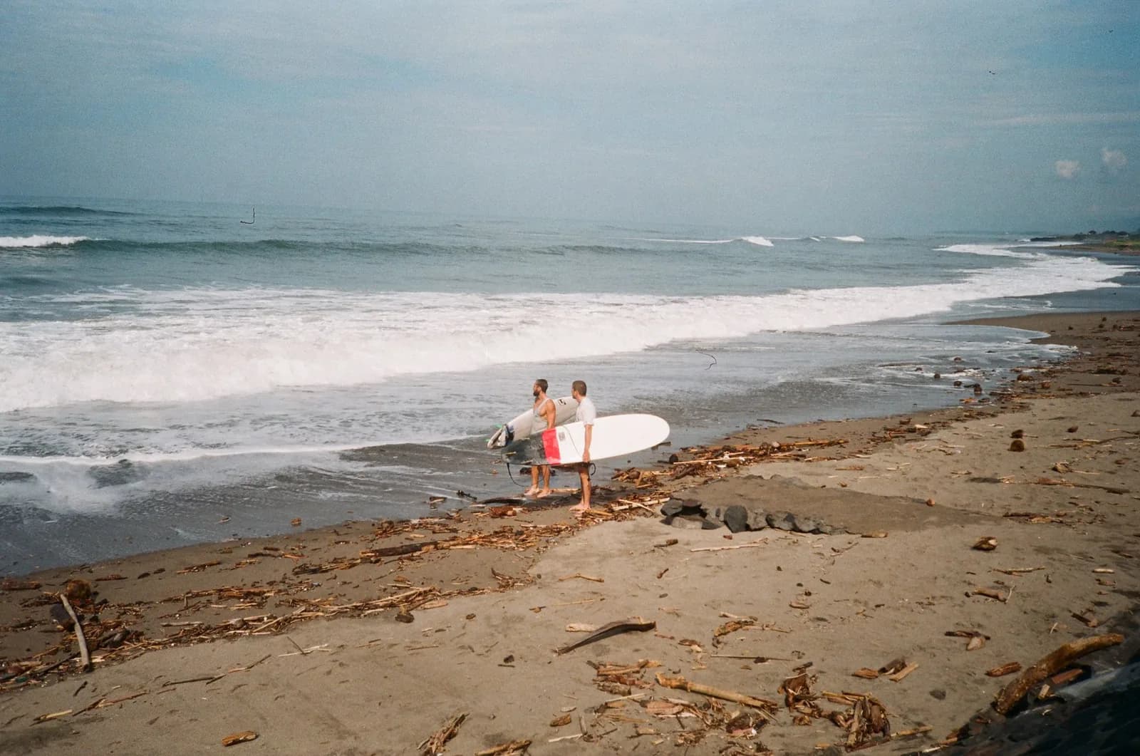 Surfeurs sur la plage de sable noir de Batu Bolong à Canggu, Bali
