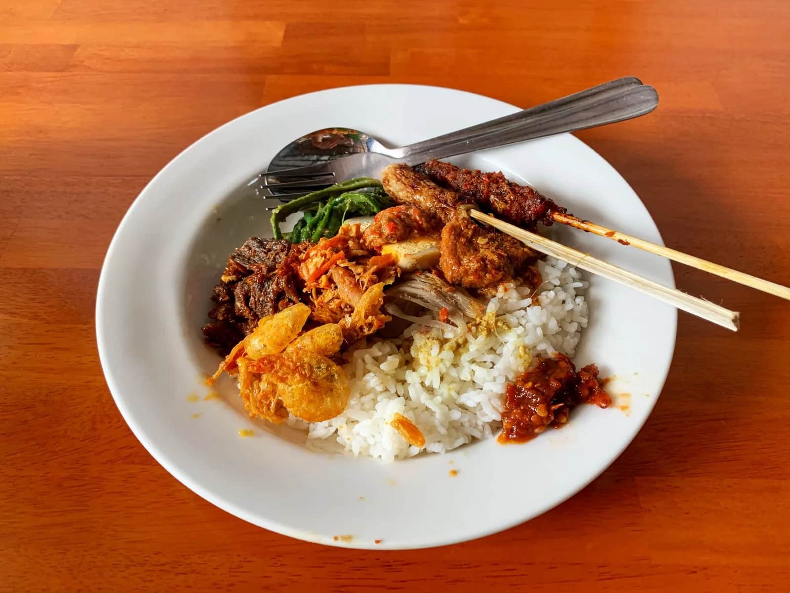 Assiette de nasi campur servie dans un warung à Bali, riz, satay et accompagnements, un repas complet à moins de 2 euros