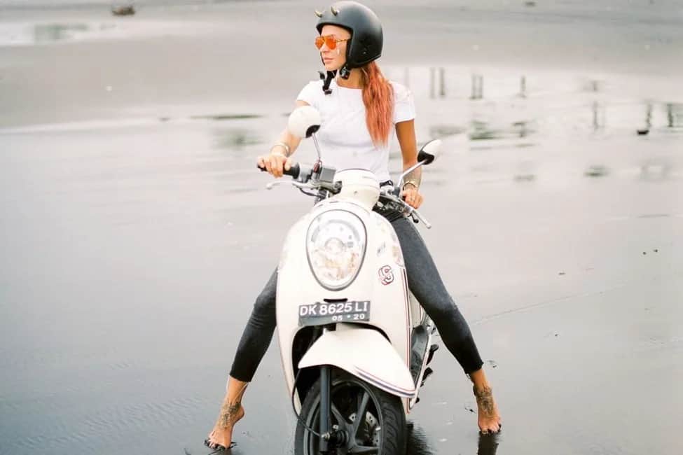 Scooter immatriculé à Bali sur une plage de sable noir, le moyen de transport quotidien des expatriés sur l'île