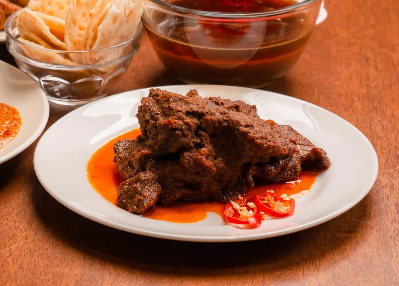 Rendang de bœuf de Padang, sauce sombre réduite, piments tranchés et krupuk