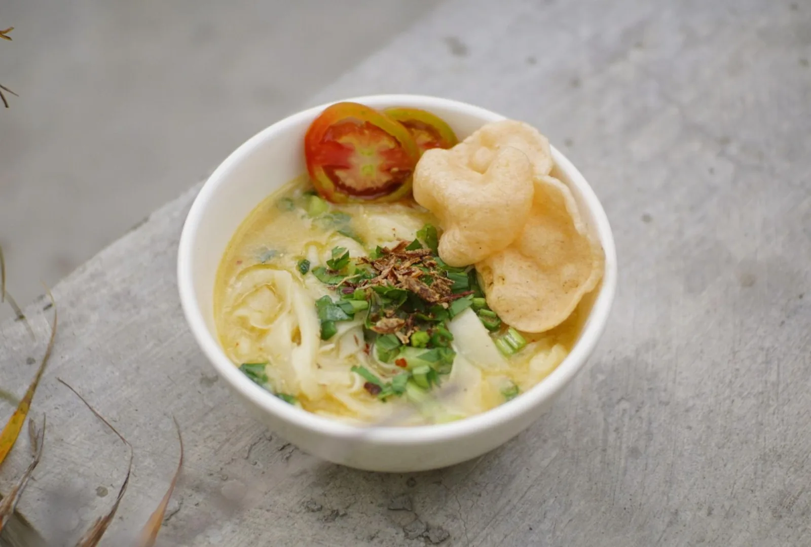 Soto ayam, soupe jaune au poulet avec tomate, échalotes frites et krupuk