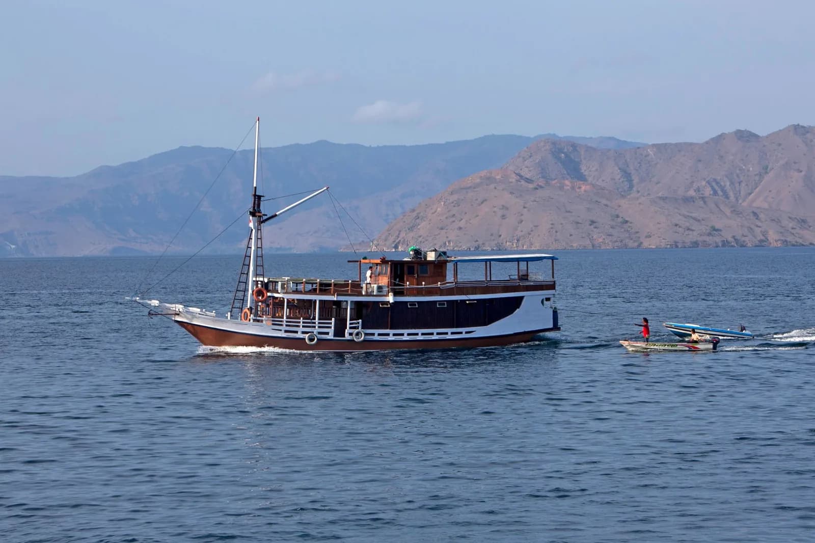 Phinisi indonésien traditionnel naviguant devant les collines sèches du détroit de Komodo, à l'ouest de Florès