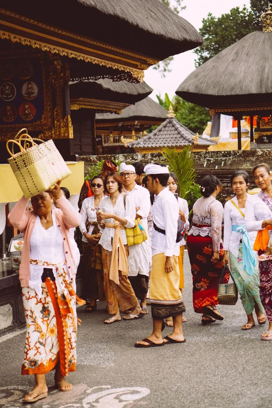 Fidèles balinais en sarong et ceinture de cérémonie à l'entrée d'un temple de Bali