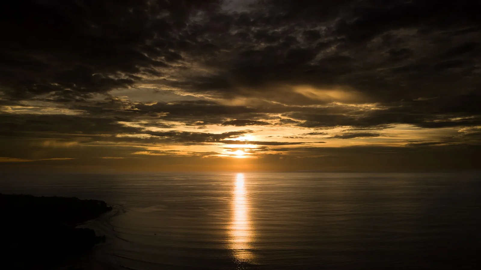 Le soleil au ras de l'horizon au-dessus de l'océan, vu depuis la côte de Bali