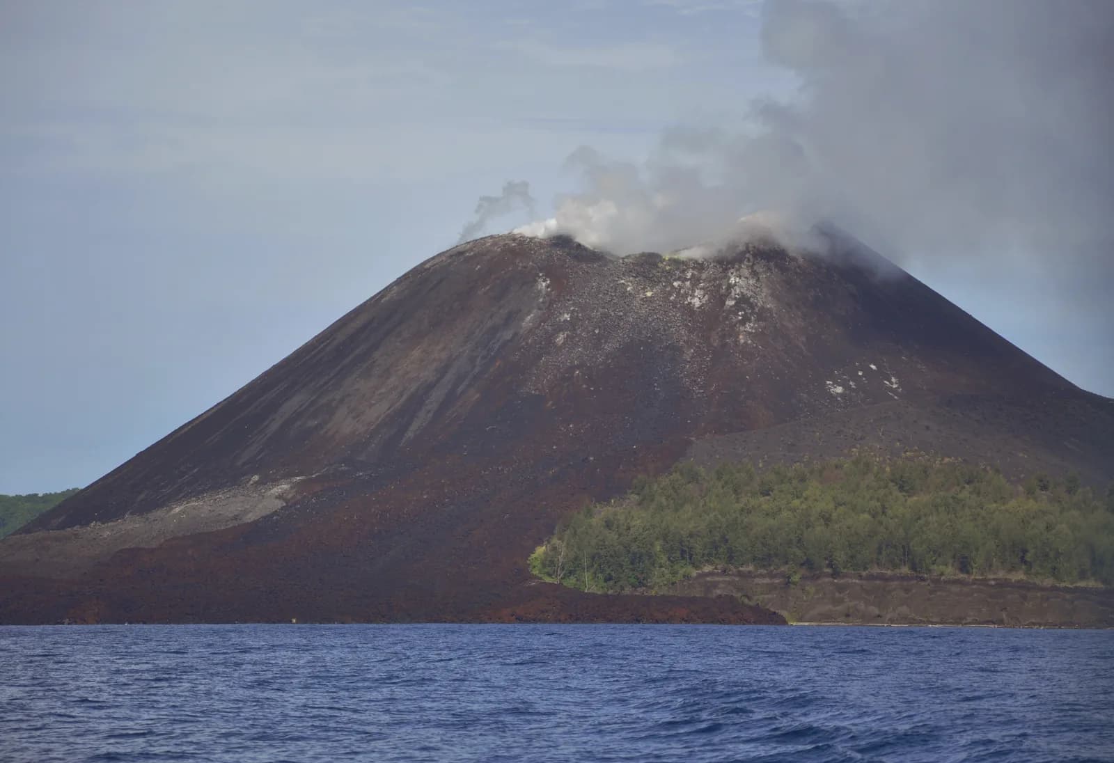Cône fumant de l'Anak Krakatau vu depuis la mer en janvier 2016, avec fumerolles au sommet et coulée de lave au pied, détroit de la Sonde