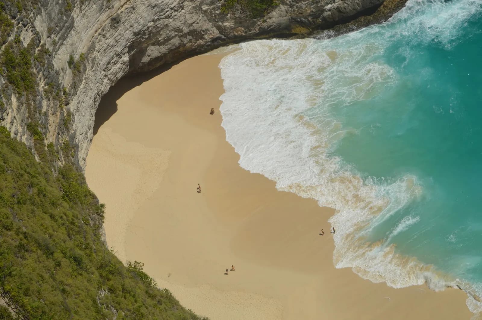 Plage de sable de Kelingking Beach vue d'en haut, vagues puissantes au pied de la falaise calcaire, Nusa Penida