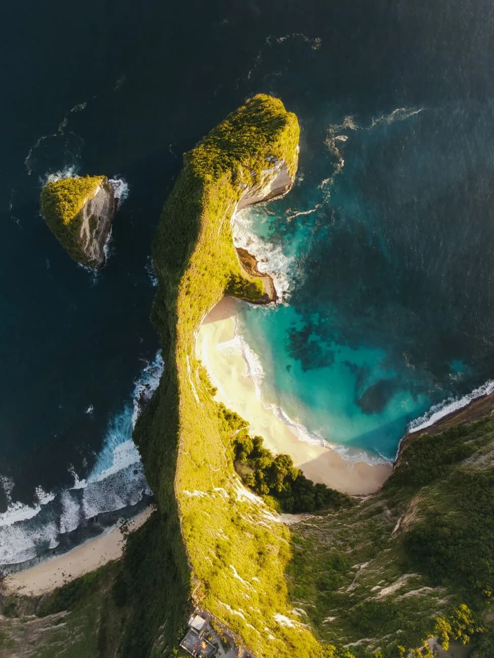 Vue aérienne de la crête de Kelingking Beach en lumière de fin de journée, avec la plage et le lagon au pied de la falaise, Nusa Penida