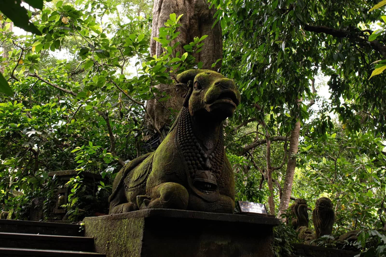 Statue de pierre moussue dans un sanctuaire balinais envahi par la jungle, ambiance de Goa Gajah