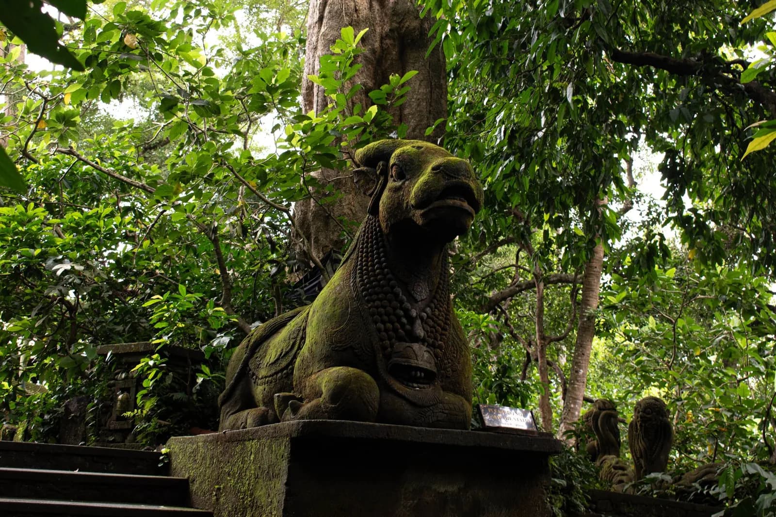 Statue de pierre moussue dans un sanctuaire balinais envahi par la jungle, ambiance de Goa Gajah