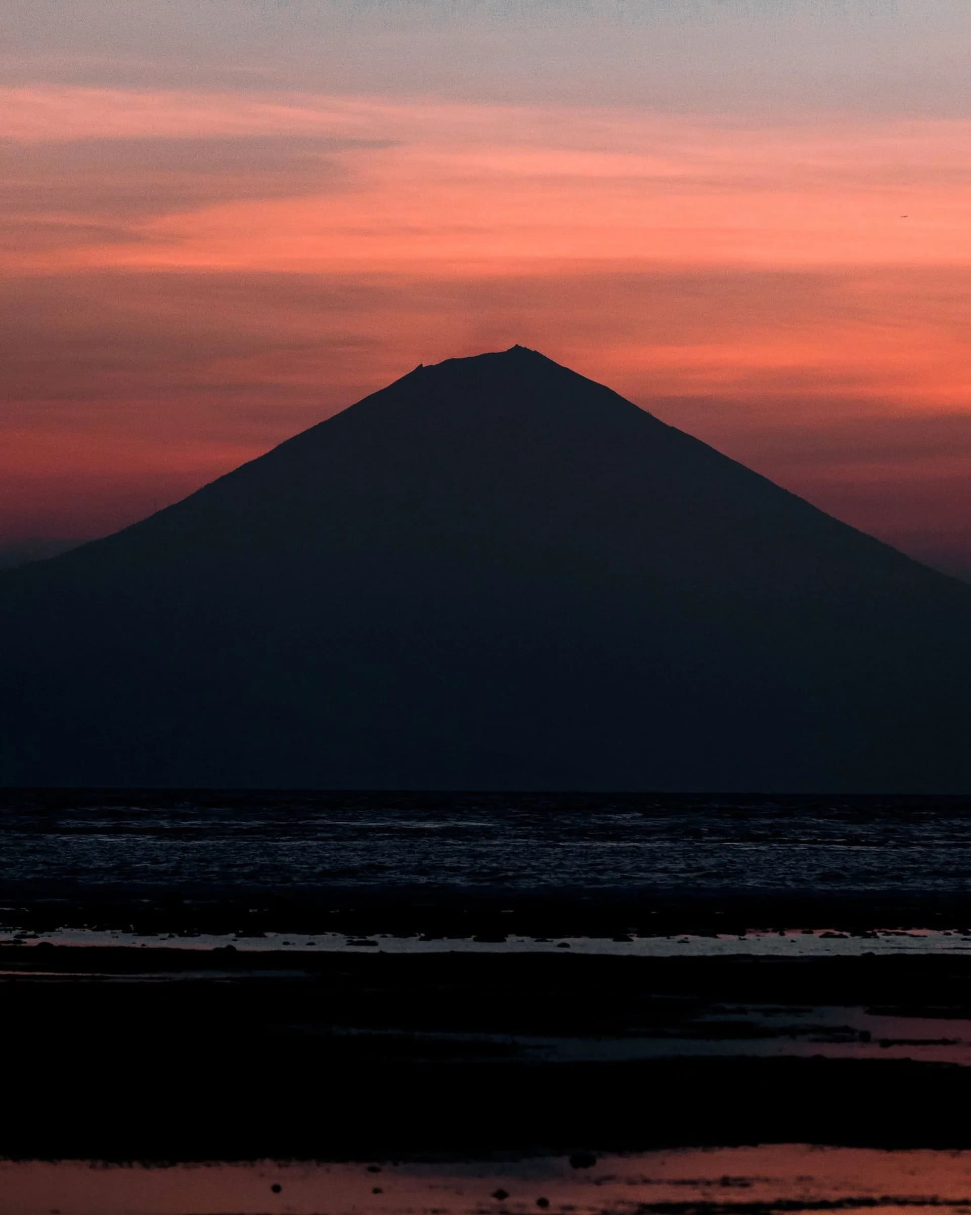 Silhouette d'un volcan au coucher du soleil depuis la côte de Lombok