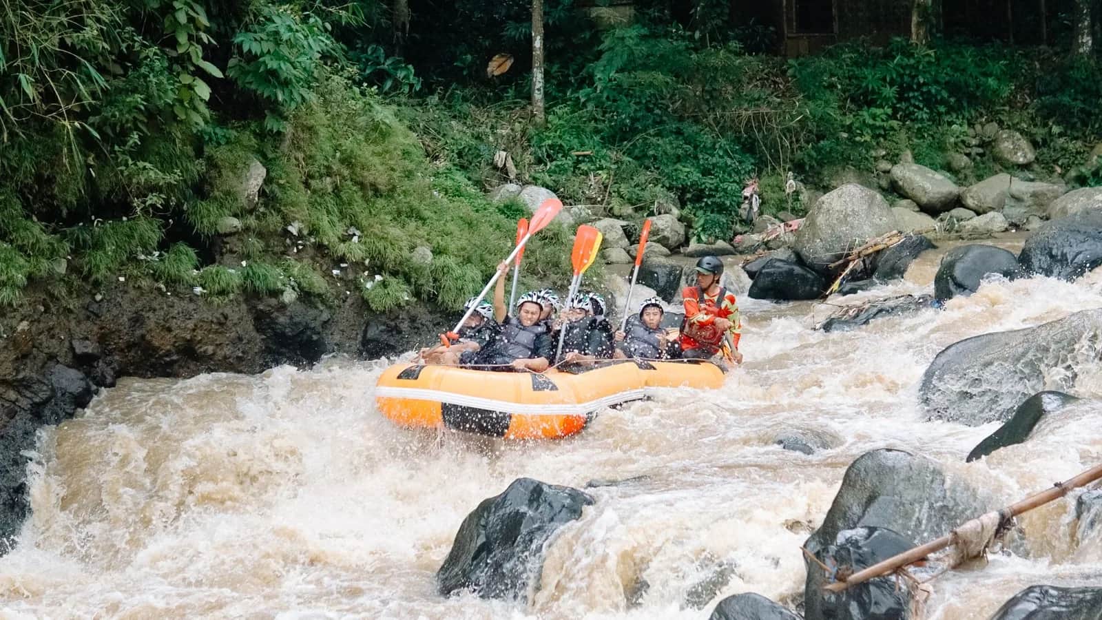 Raft pneumatique orange dans les rapides d'une rivière bordée de jungle, Bali