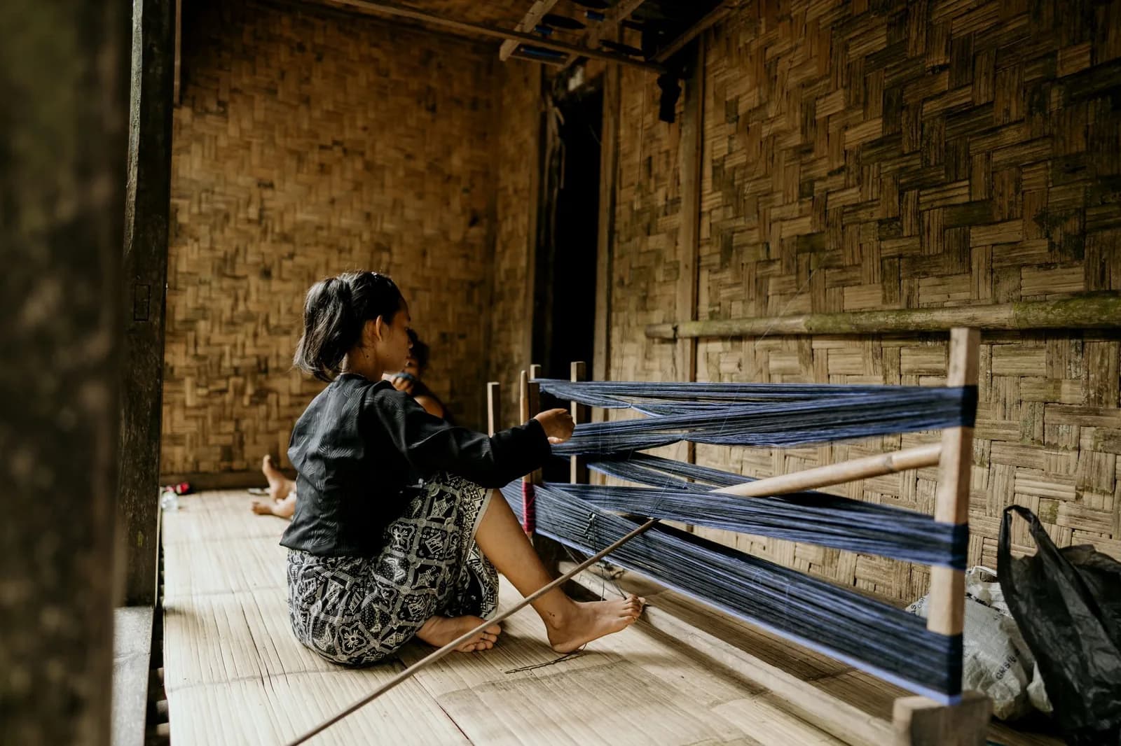 Tisserande assise devant un métier à tisser traditionnel en bois, Indonésie