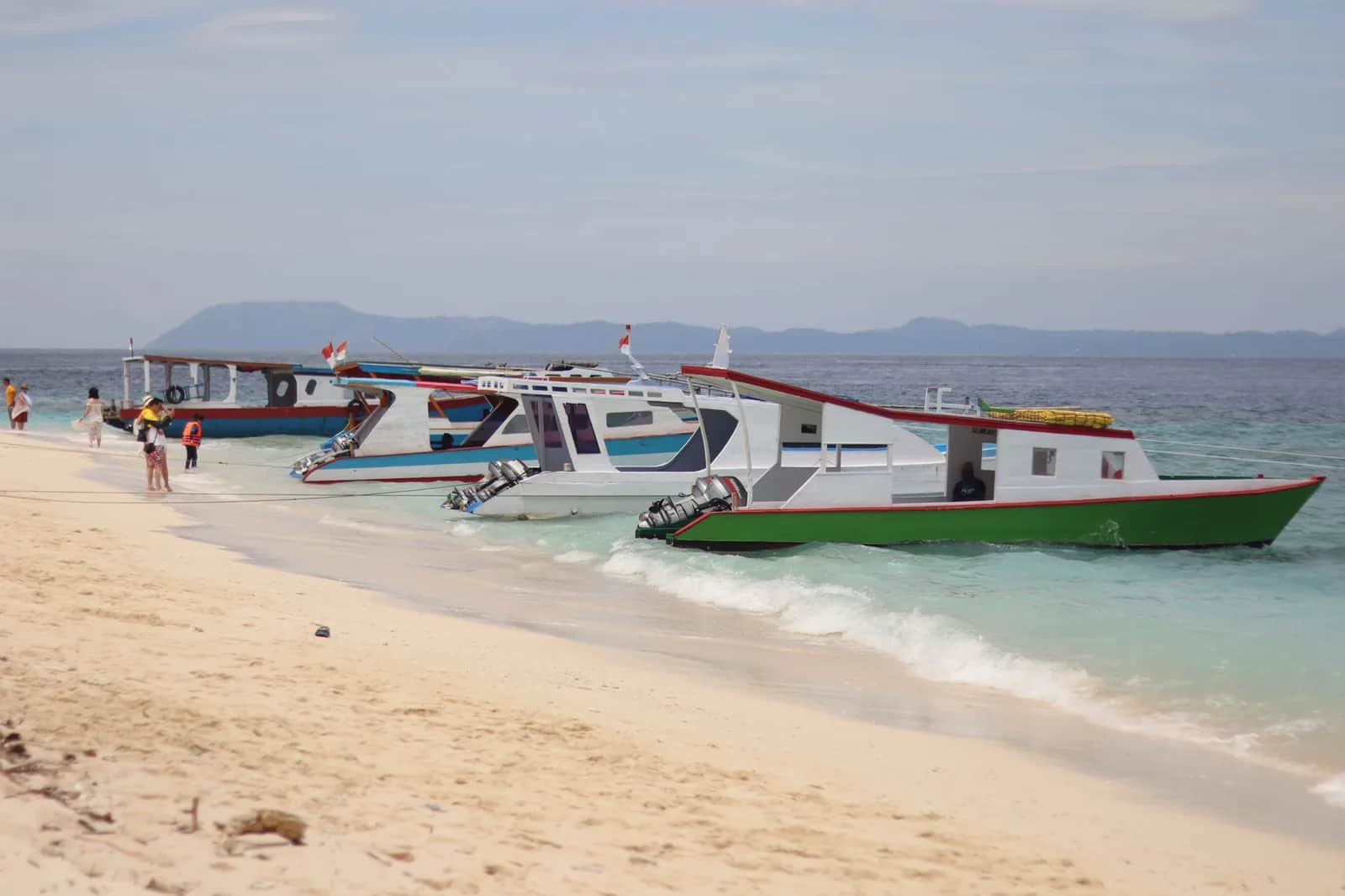 Bateaux rapides à moteurs hors-bord amarrés le long d'une plage de sable blanc en Indonésie