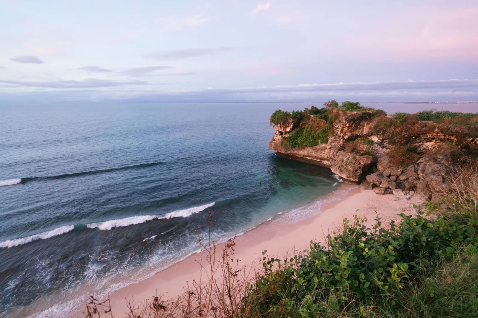 Crique de sable au pied des falaises de la péninsule du Bukit au crépuscule, Uluwatu, Bali