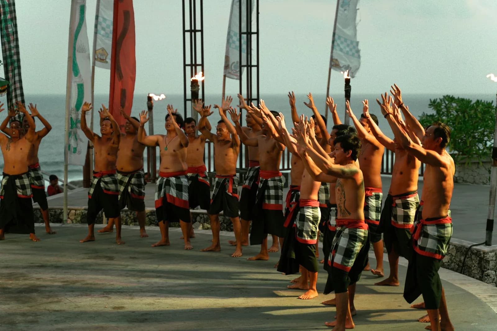 Danseurs du Kecak bras levés devant les torches et l'océan, à Uluwatu, Bali