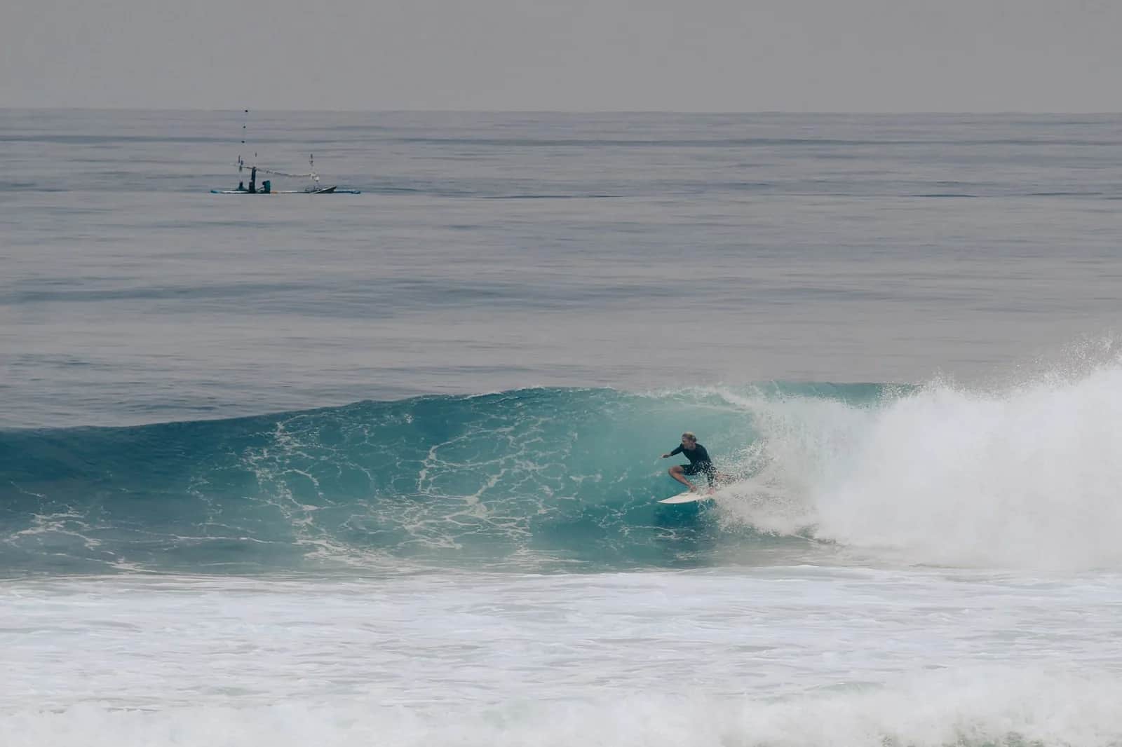 Surfeur dans une gauche déferlant au pied des falaises d'Uluwatu, Bali