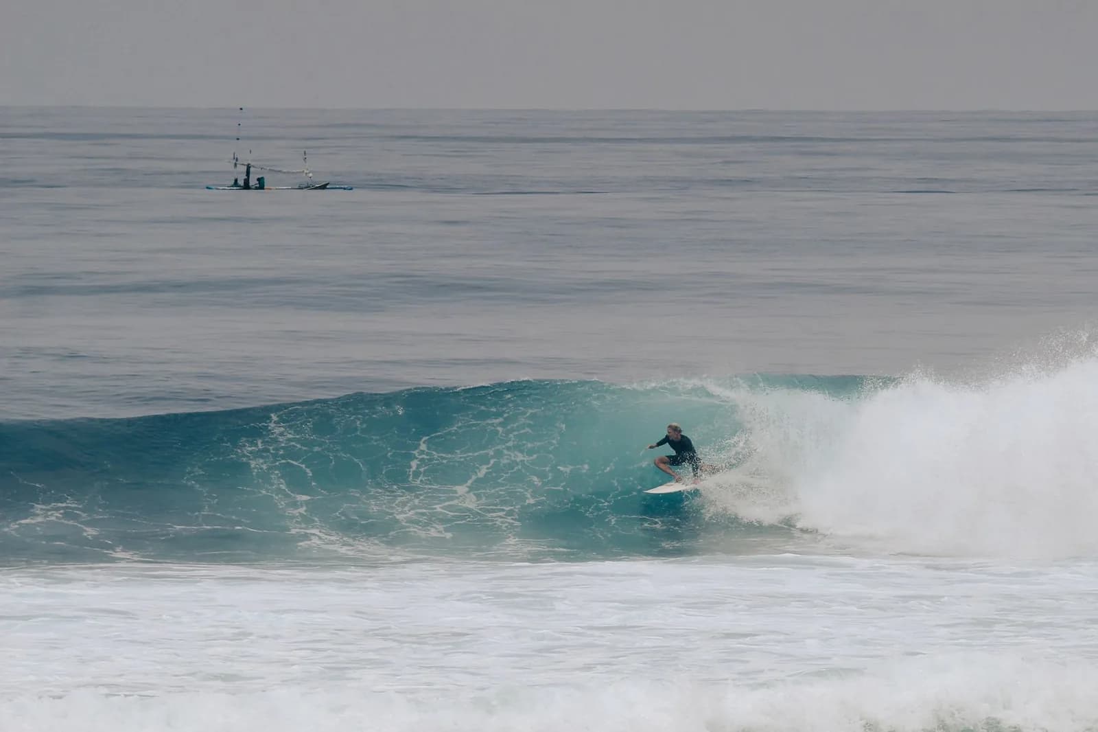 Surfeur dans une gauche déferlant au pied des falaises d'Uluwatu, Bali
