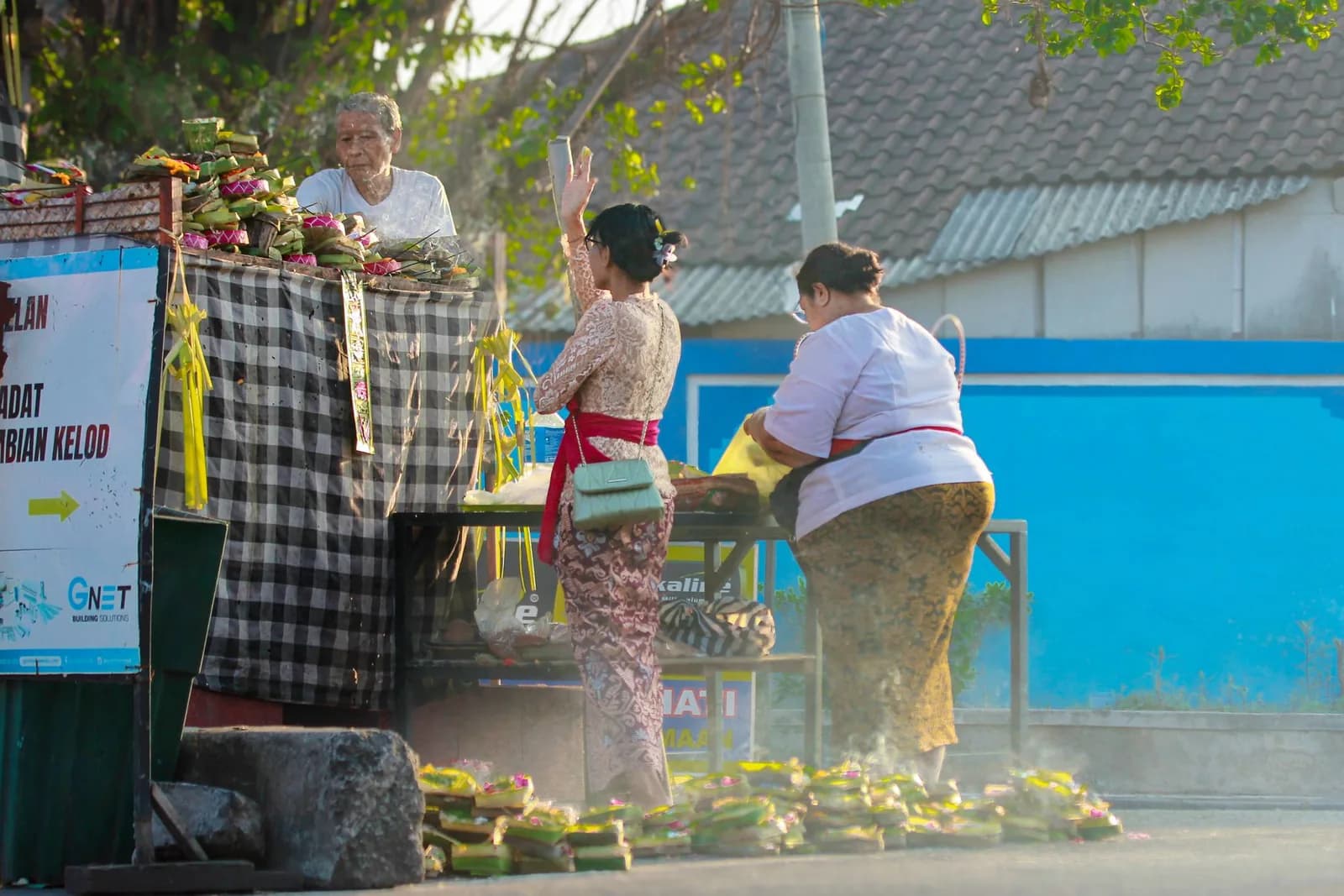 Femmes balinaises en tenue traditionnelle achetant des offrandes quotidiennes sur un marché de Denpasar, Bali