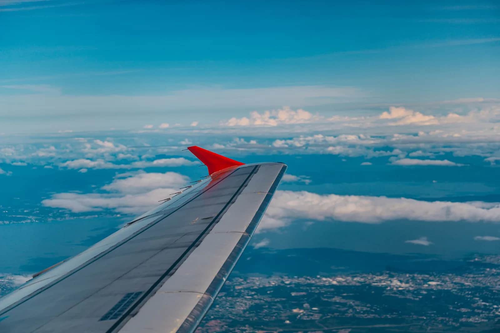 Aile d'avion en vol au-dessus d'une côte tropicale, cap sur Bali