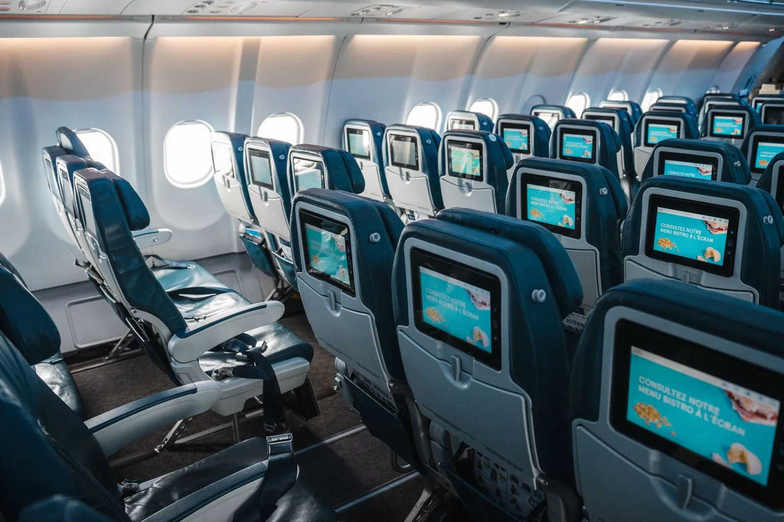 Cabine économique d'un long-courrier en route vers Bali, écrans individuels allumés