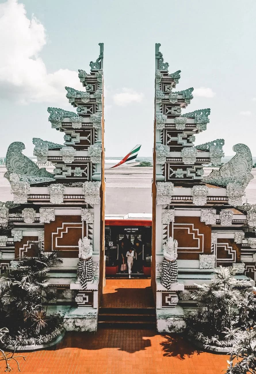 Porte balinaise sculptée à l'aéroport Ngurah Rai de Denpasar, avion long-courrier sur le tarmac