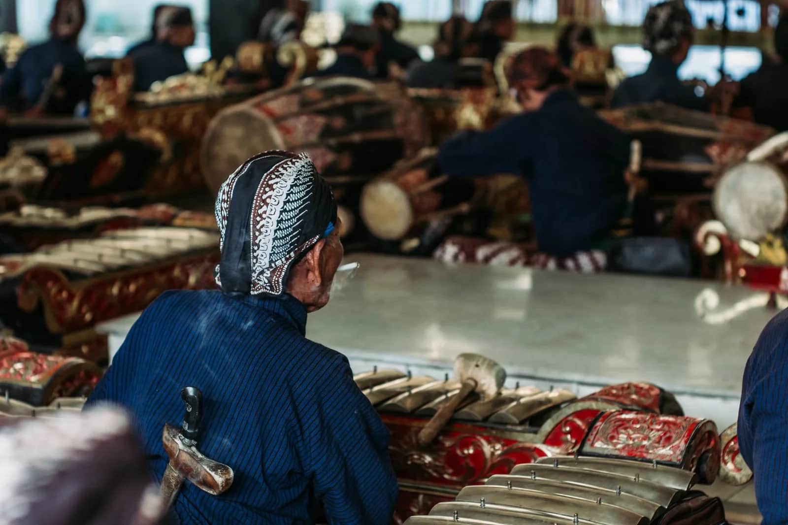 Musicien javanais en blangkon devant les gongs et métallophones d'un gamelan à Yogyakarta